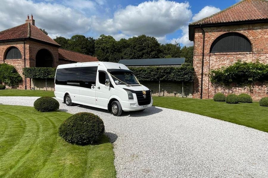White 16-seater Volkswagen Crafter minibus dressed with wedding ribbon at a barn wedding venue
