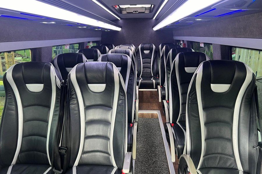 Interior of the ATS Travel 16-seater executive minibus showing black and white leather reclining seats and ambient LED lighting
