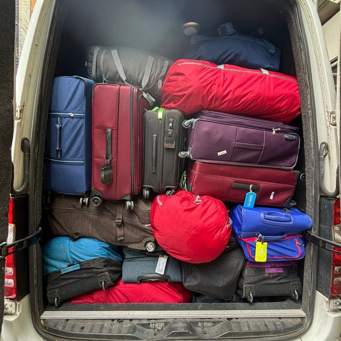 Rear luggage compartment of an ATS Travel minibus fully loaded with sixteen passengers' suitcases and holdalls